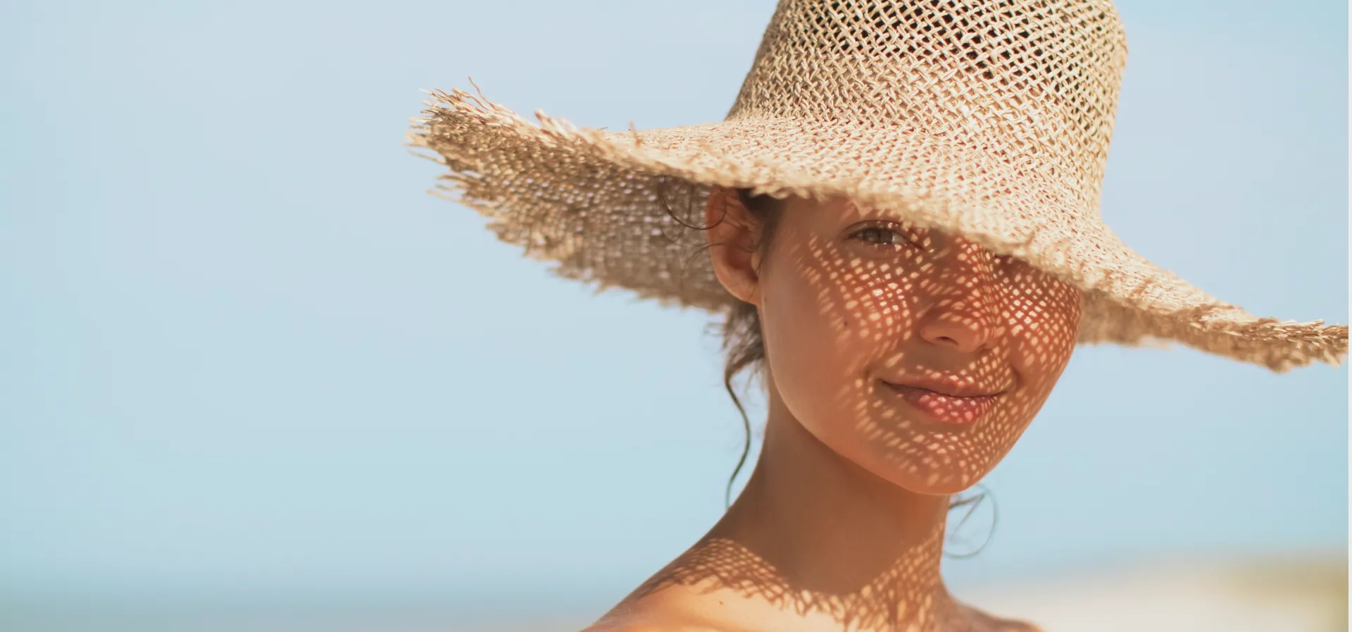 A smiling woman in a sun hat on a Kailua Kona beach